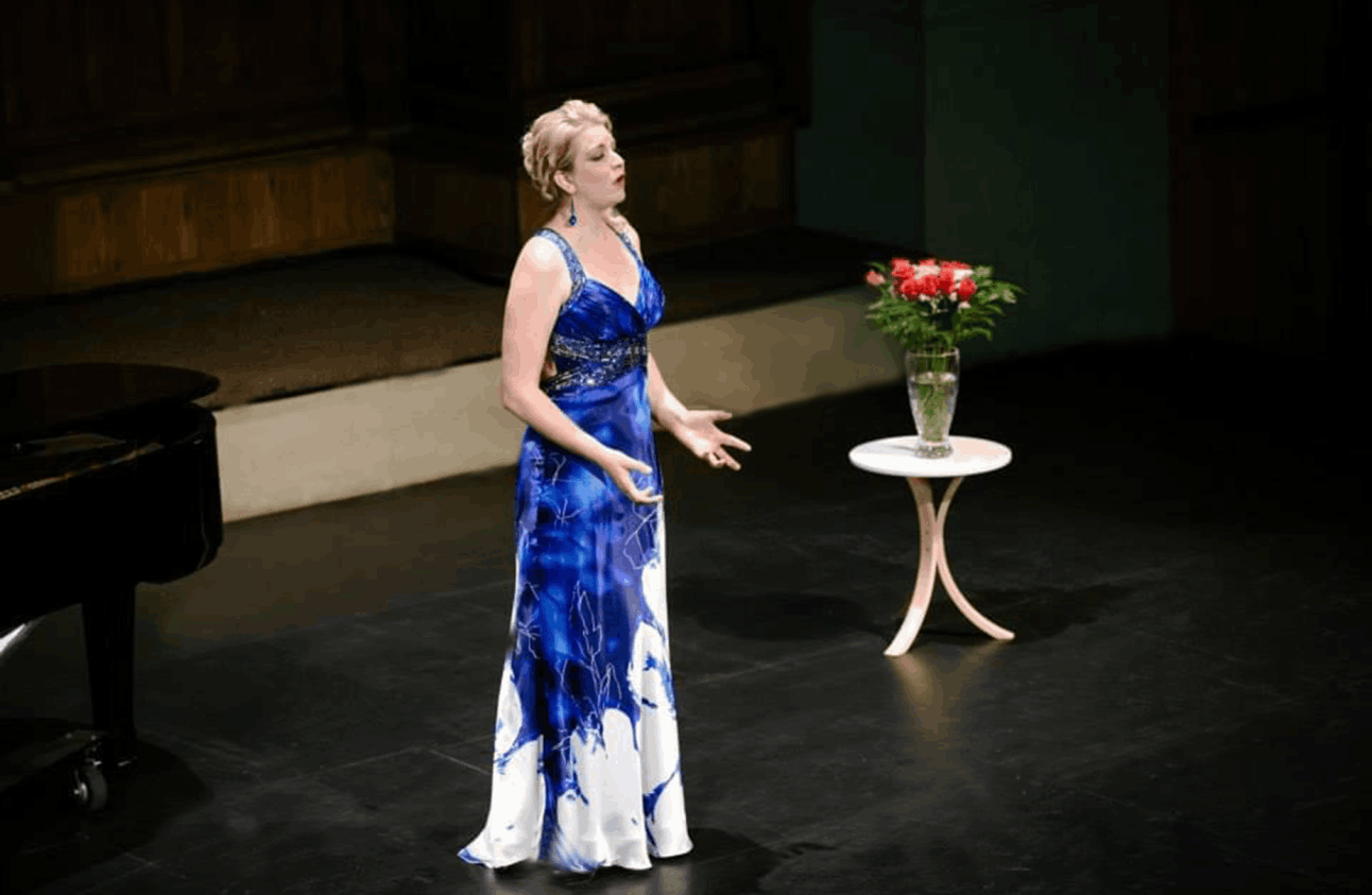 Mia Singing on stage as a Mezzo Soprano is wearing a blue dress to show her support for the Concert Calgary foundation